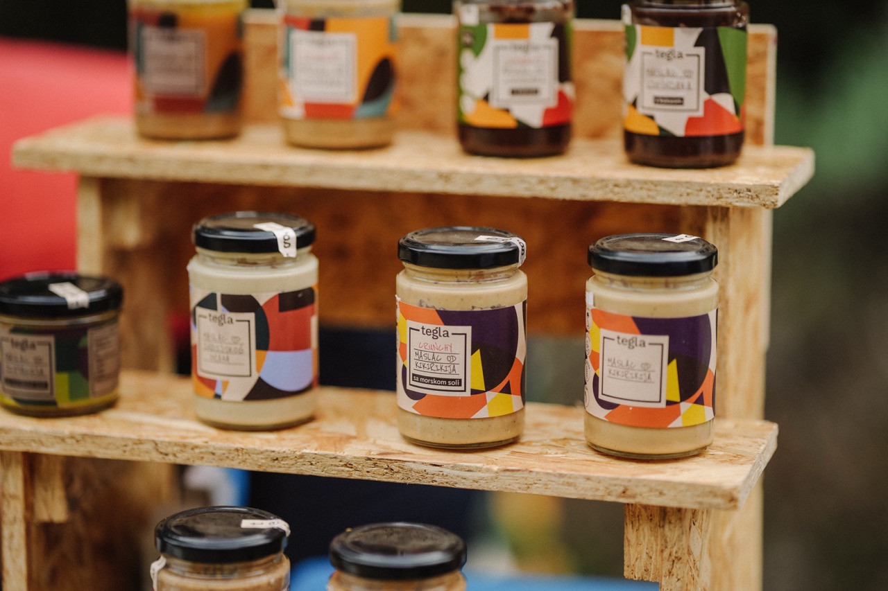 jars of colorful labeled nut butters displayed on wooden shelves outdoors