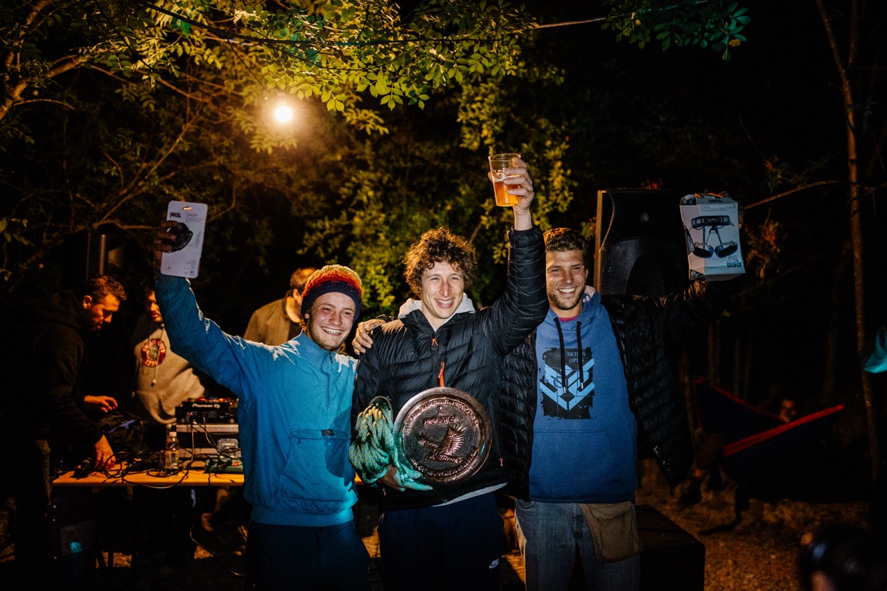 three young men celebrating with awards and a drink at an outdoor nighttime event