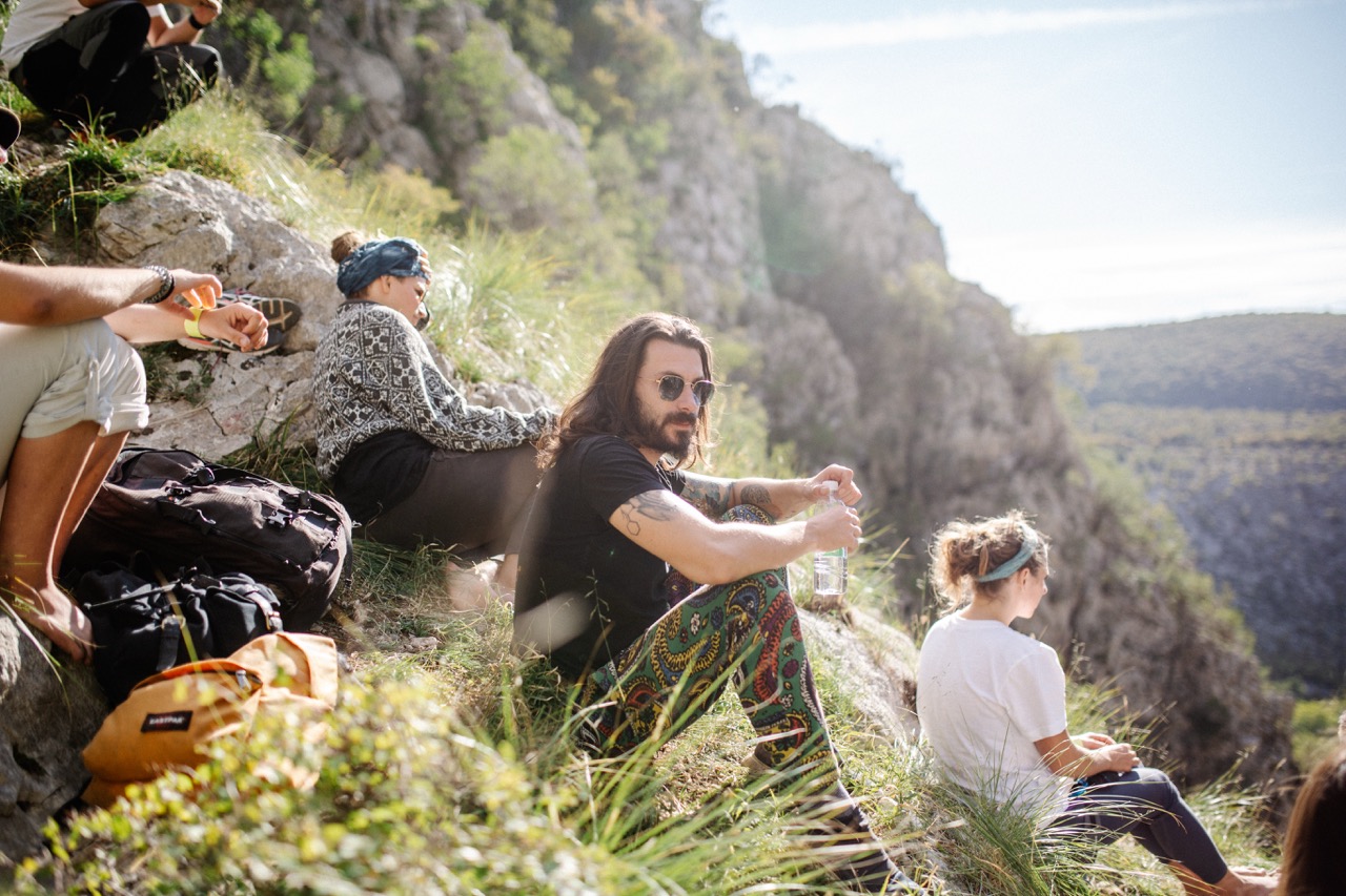 group of friends resting on hillside with backpacks and scenic mountain view