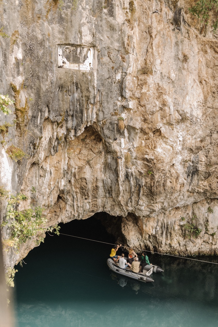 people on a small boat entering a large rocky cave with dark water inside