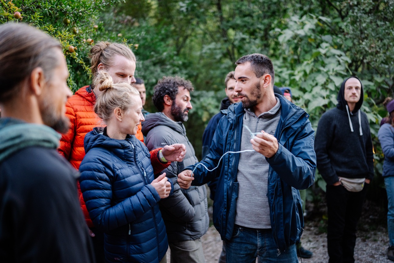 group of outdoors people wearing jackets interacting and chatting in a forested area