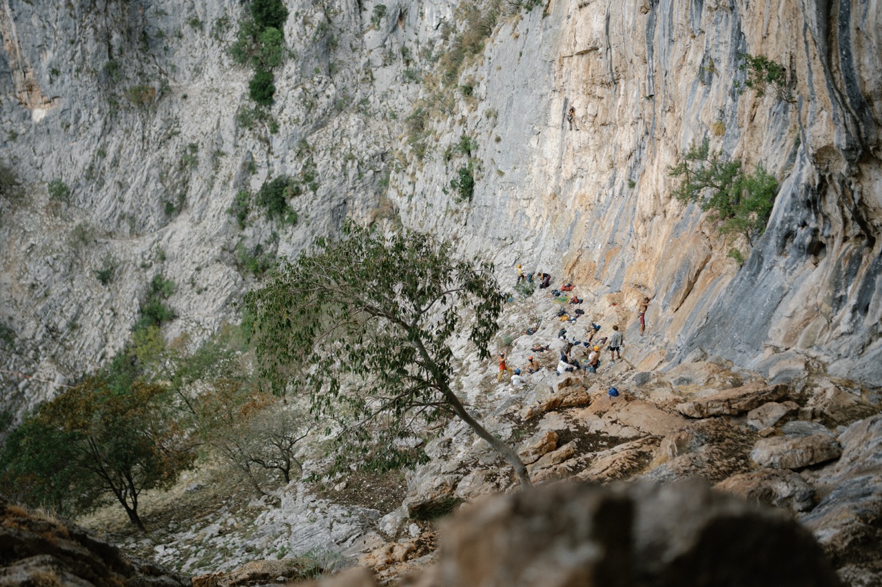 group of people rock climbing and resting at the base of a steep rocky cliff