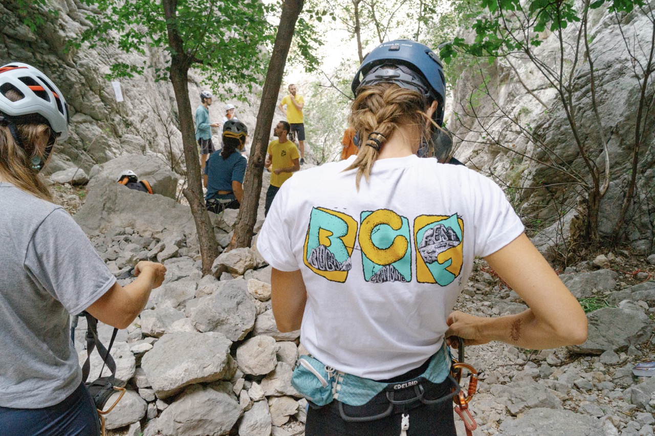 group of people in helmets and climbing gear preparing for rock climbing in rocky outdoor setting