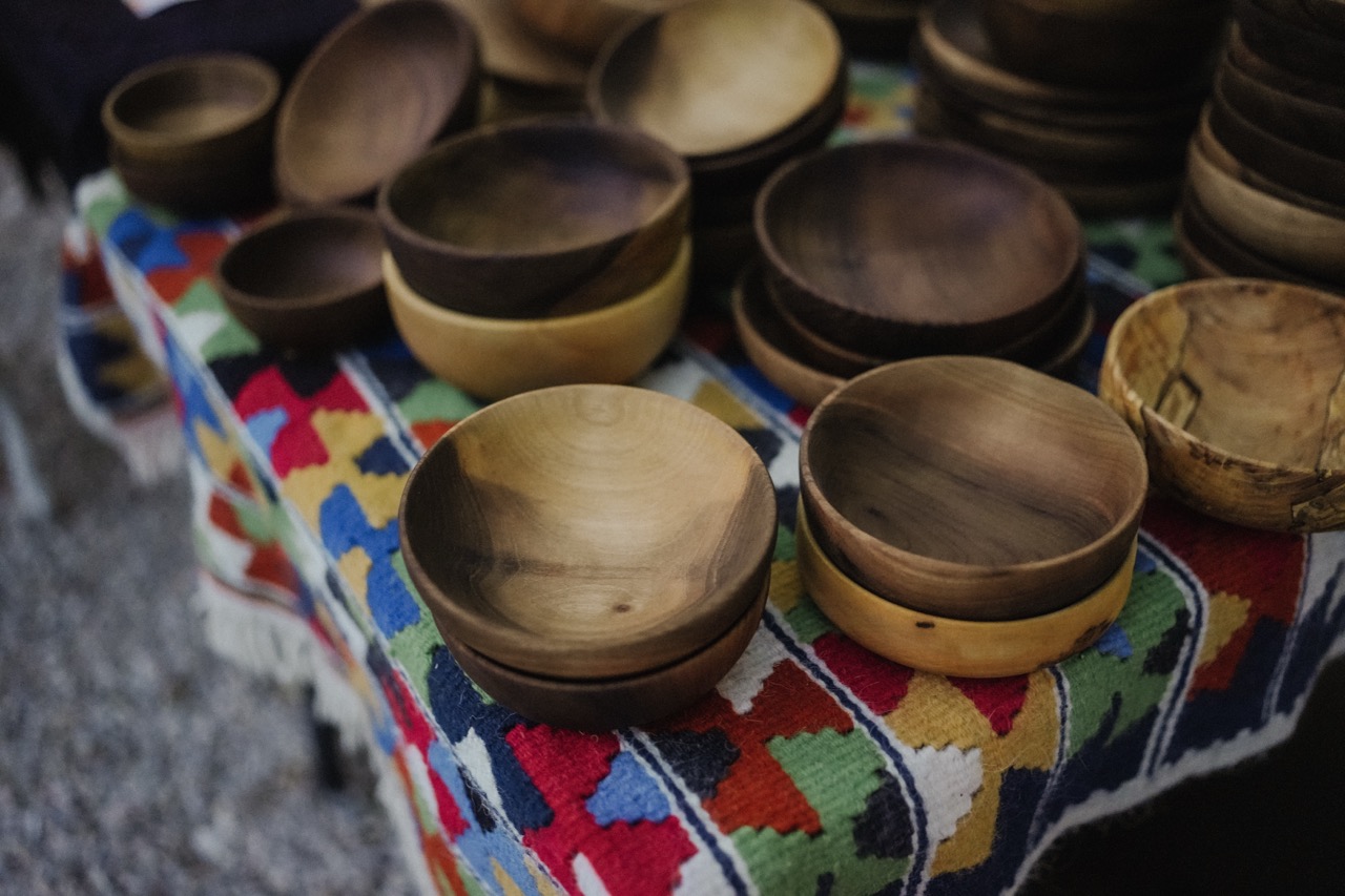 handcrafted wooden bowls of various sizes stacked on a colorful patterned tablecloth