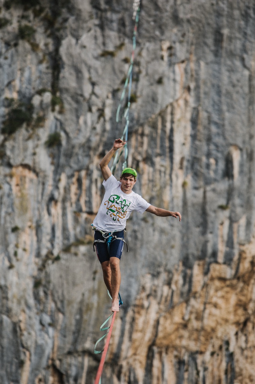 man balancing on a slackline in front of a rocky cliff