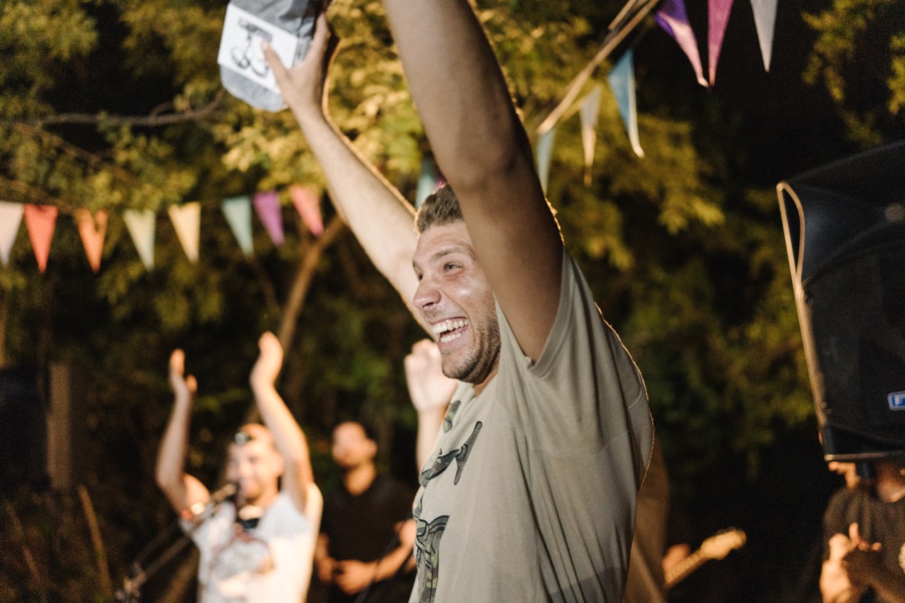 man cheering with raised arms at an outdoor night party with colorful flags