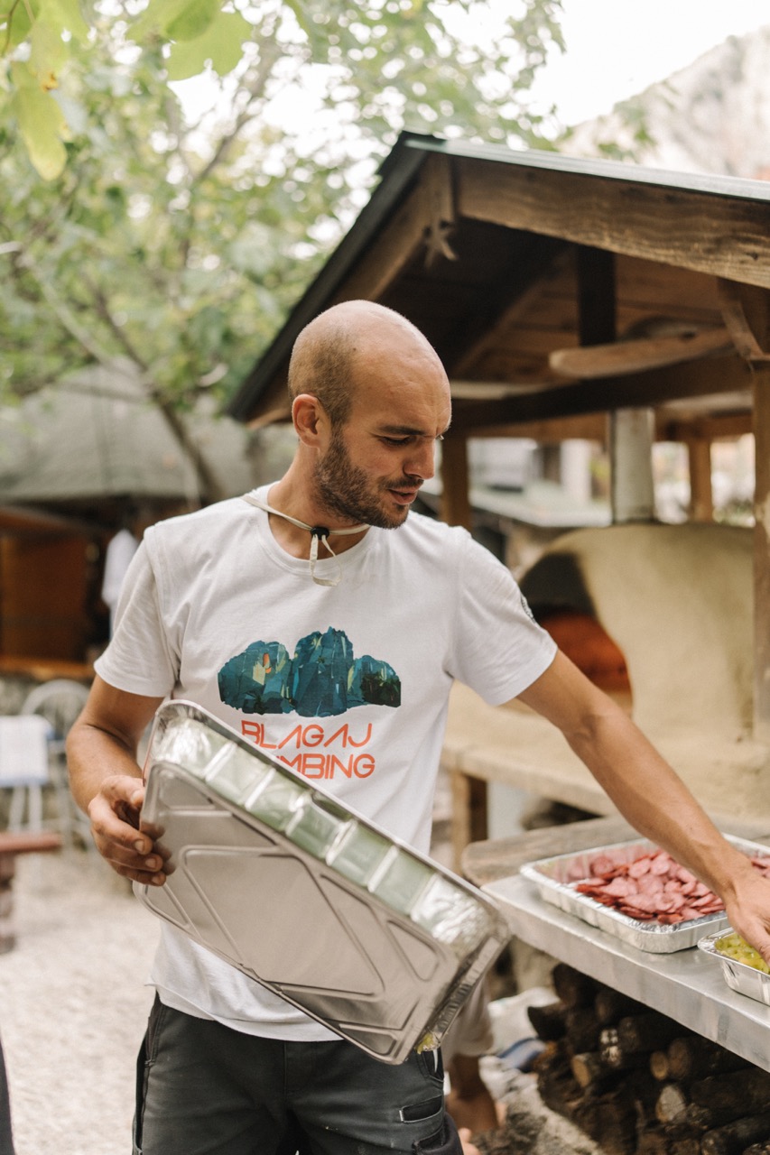man holding a large metal tray while preparing food outdoors