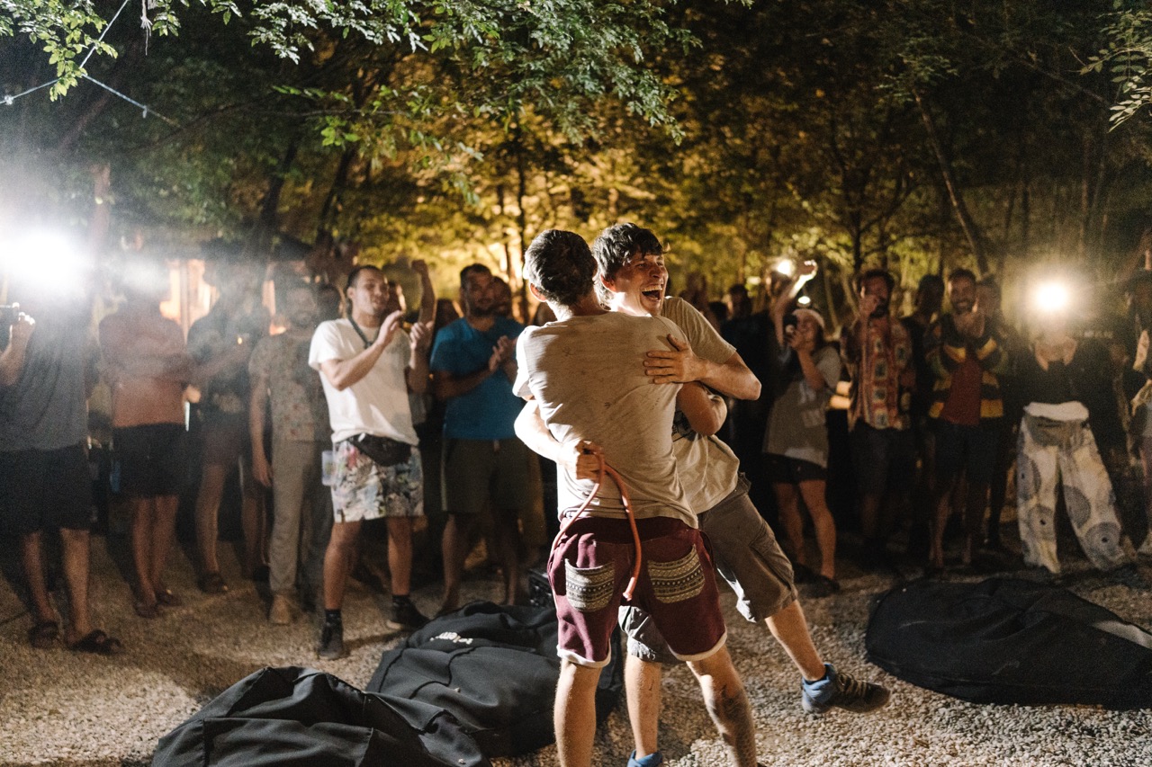 two young men hugging and celebrating in front of a crowd at night with people taking photos