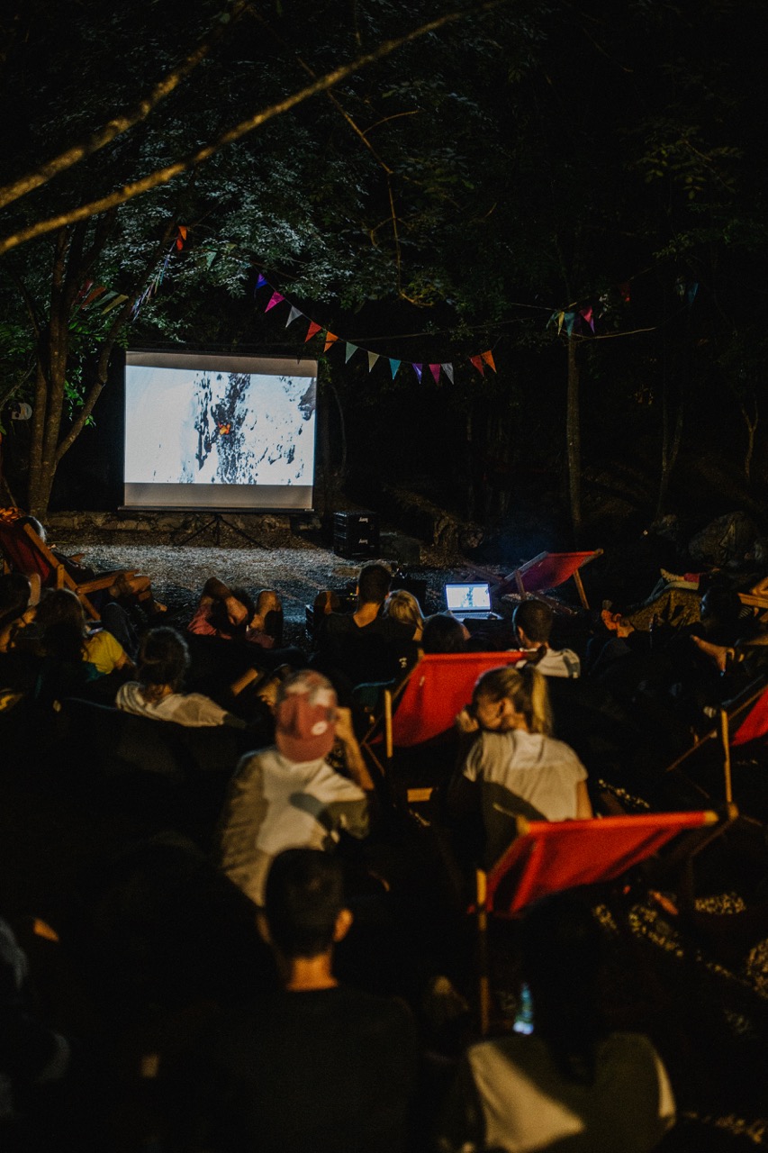 outdoor movie night with people sitting in chairs watching a film on a projector screen at night