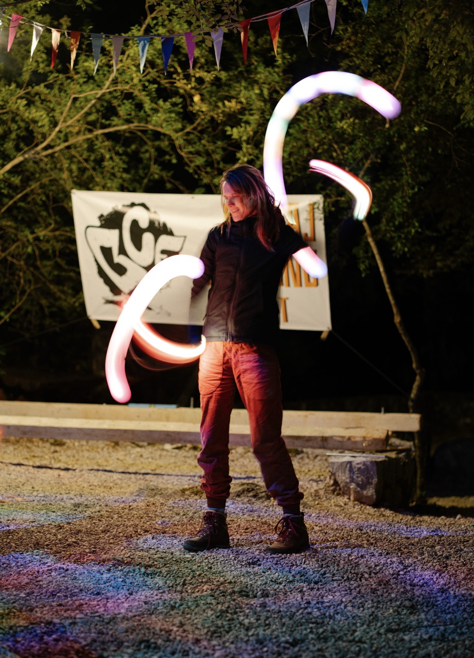 person performing illuminated poi spinning at night with light trails