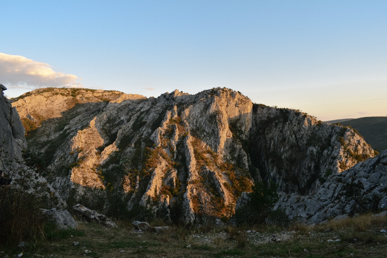 rocky mountain ridge with sunlight casting warm shadows under a clear blue sky