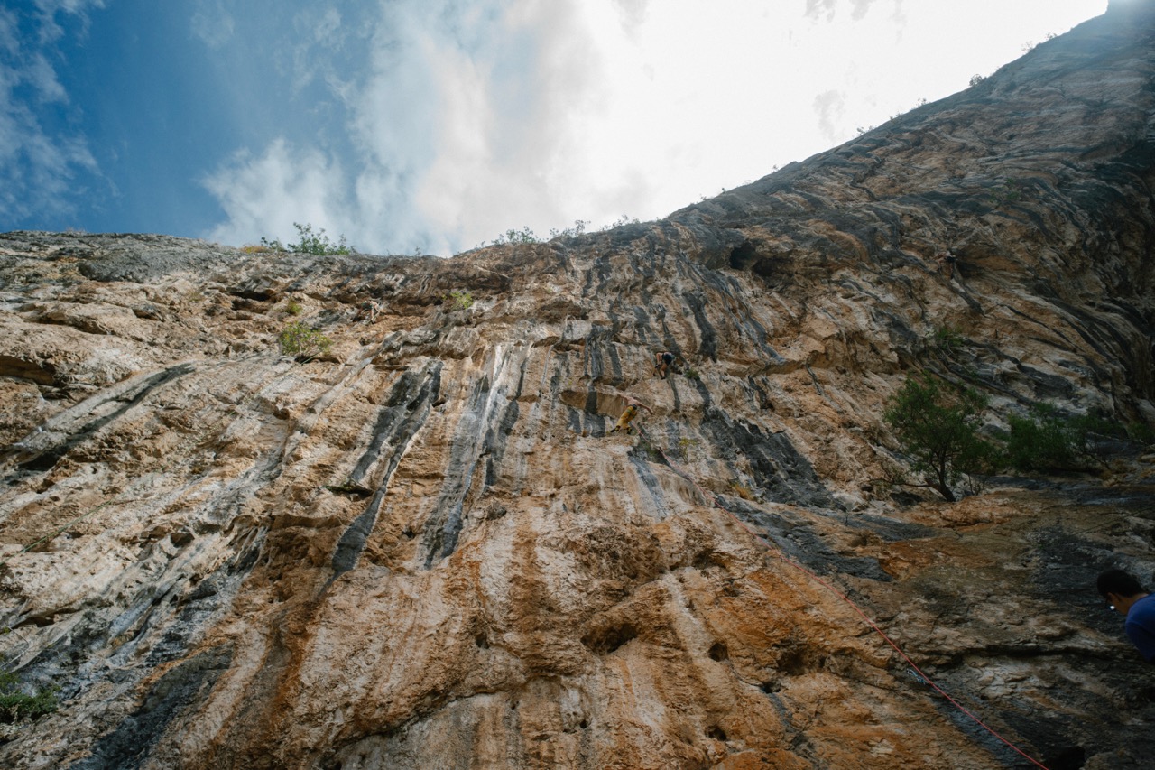 people rock climbing on a steep cliff with climbing ropes and gear