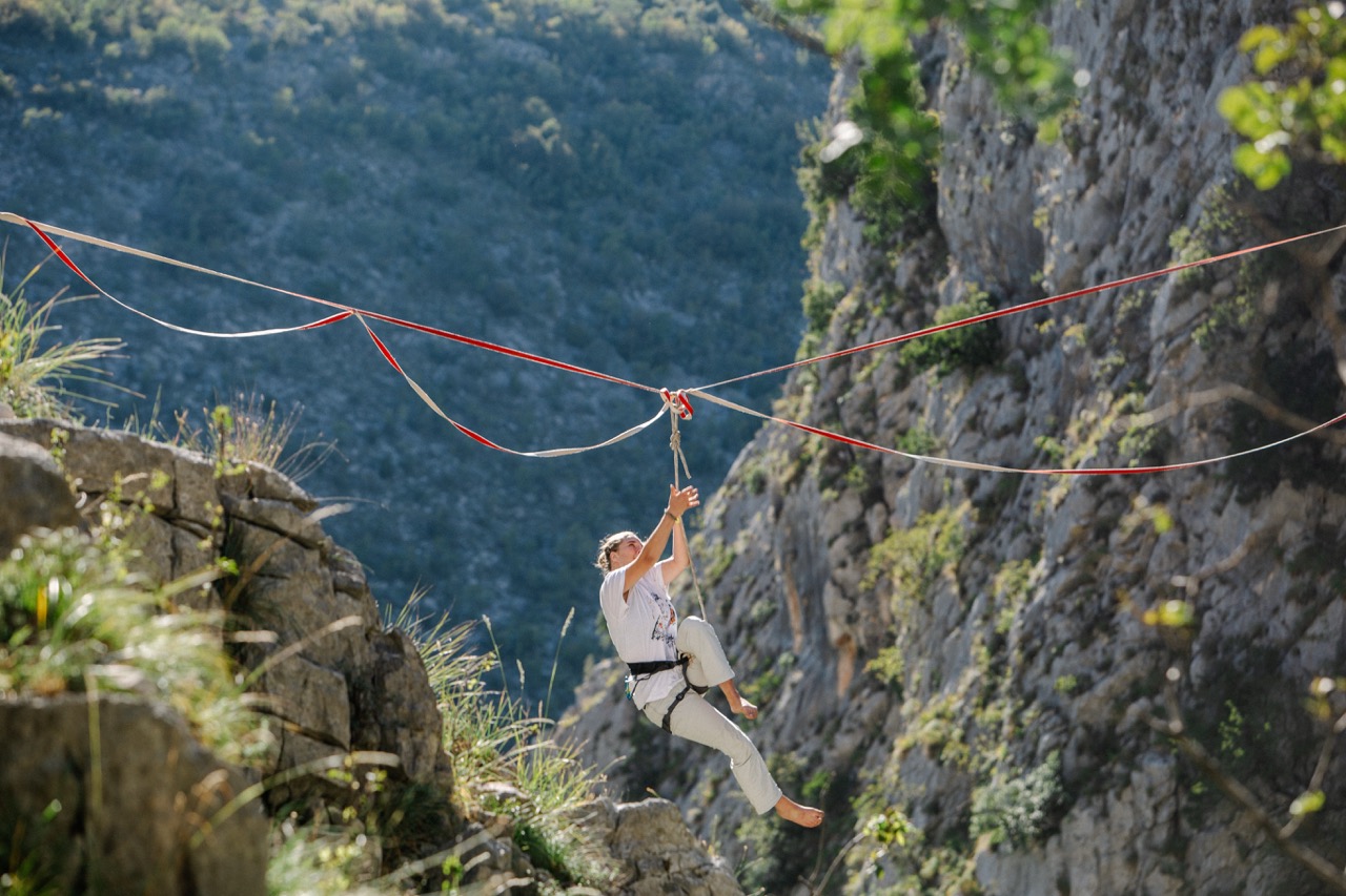 woman suspended on a rope ziplining between rocky cliffs in a mountainous area